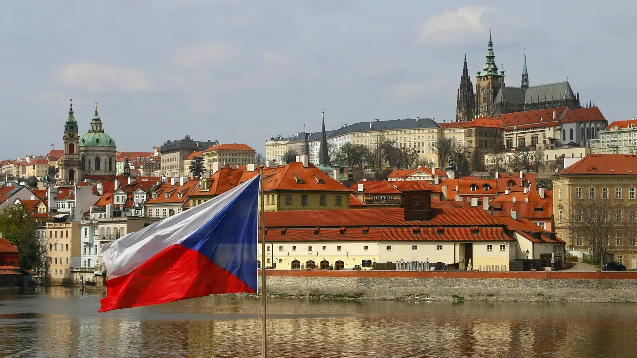 The Czech flag flying over the Vltava, with the red roofs of Malá Strana and Prague Castle behind