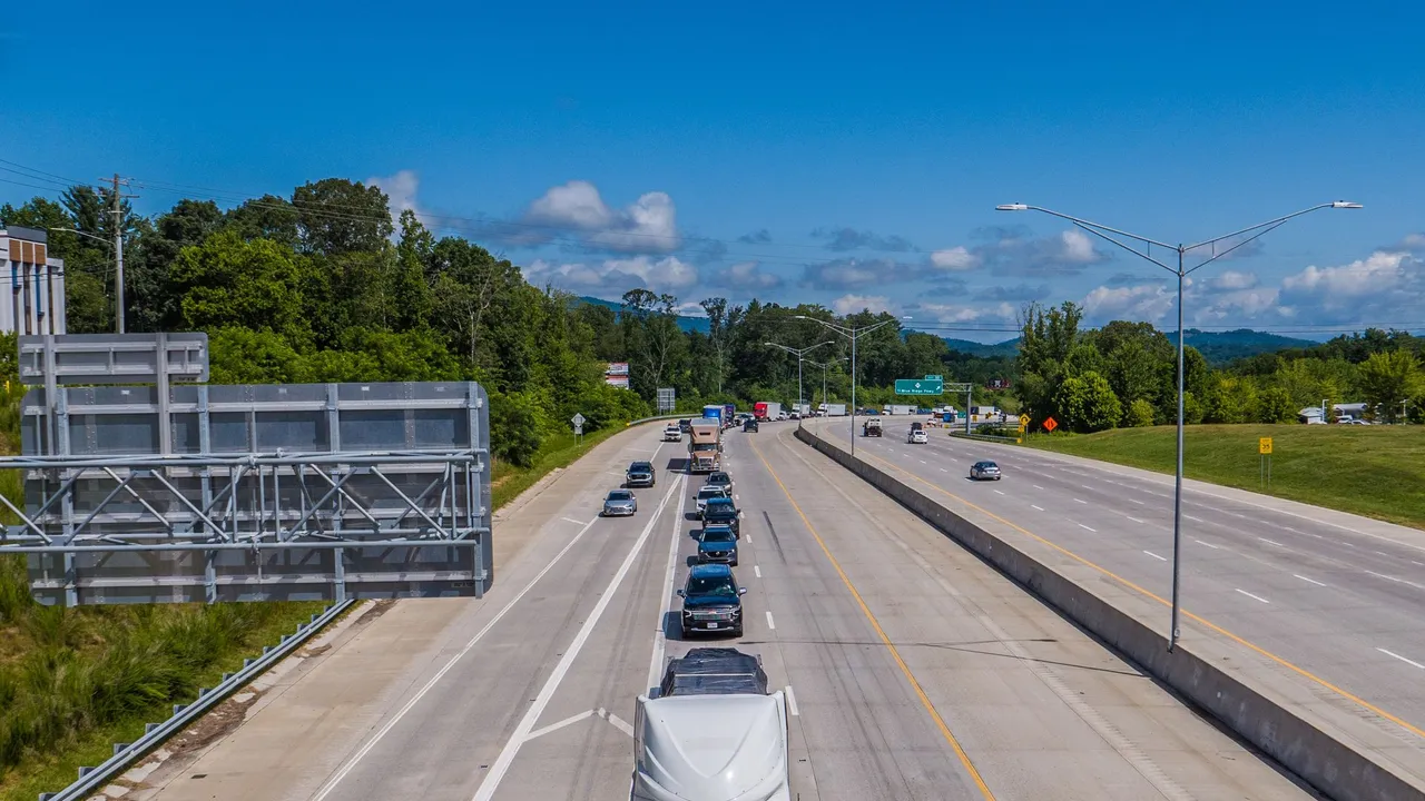 A toll-road carriageway with gantry infrastructure and traffic under a bright sky