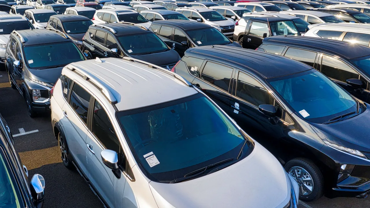 Rows of parked passenger cars in a dense fleet-style lot on a clear day