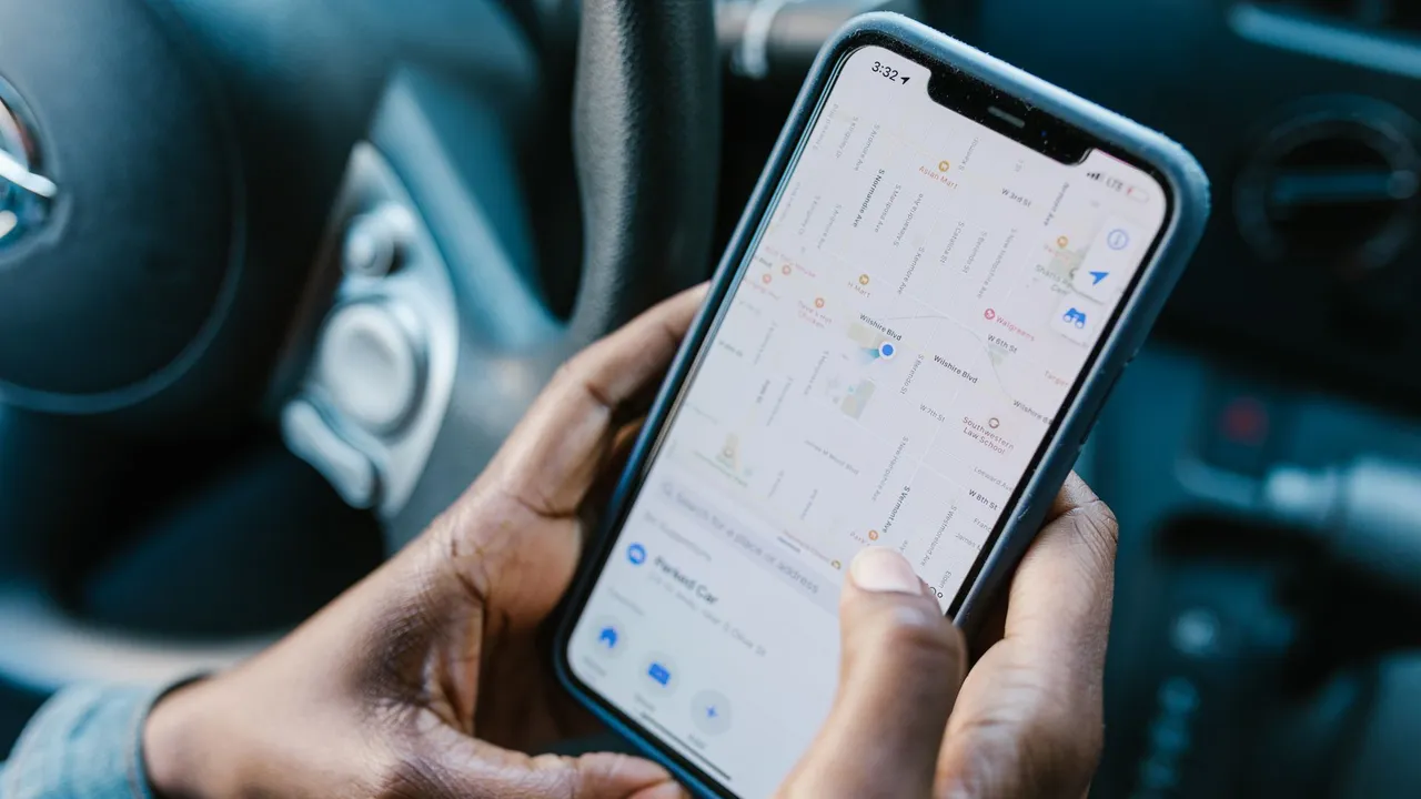 A driver holding a smartphone with navigation open inside a car