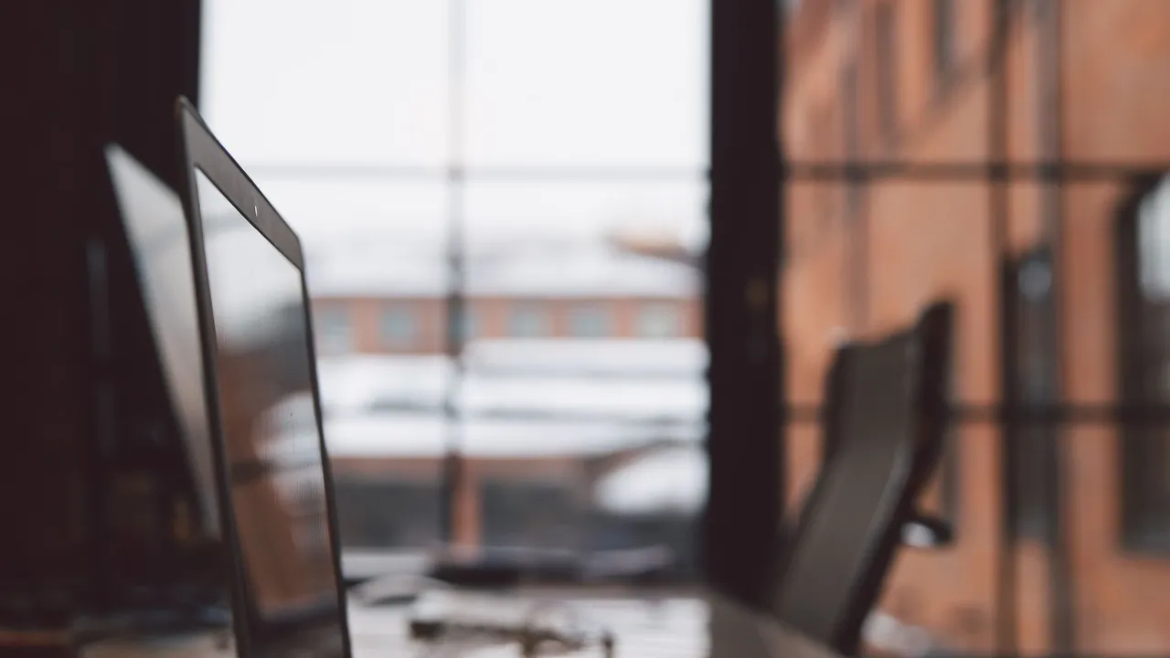Office monitors on a desk in soft focus by a window