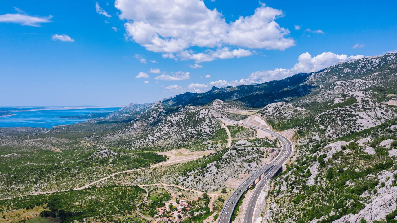 A coastal motorway winding through rocky terrain above the Adriatic shore