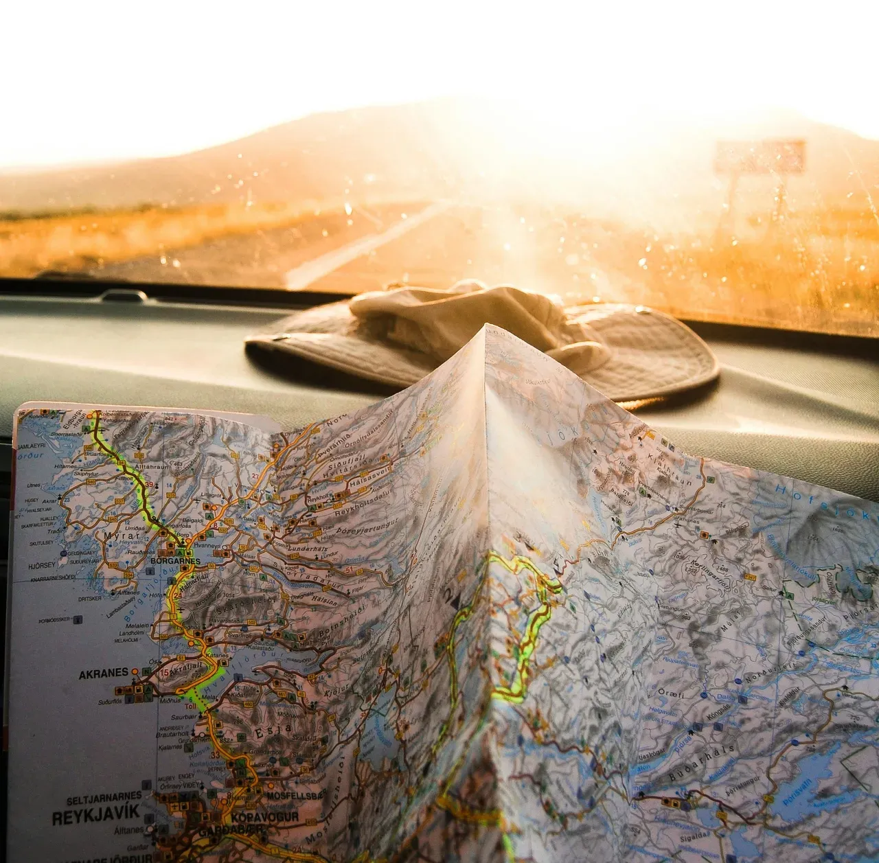 Carte routière en papier et chapeau de voyage sur le tableau de bord d'une voiture pendant un road trip européen
