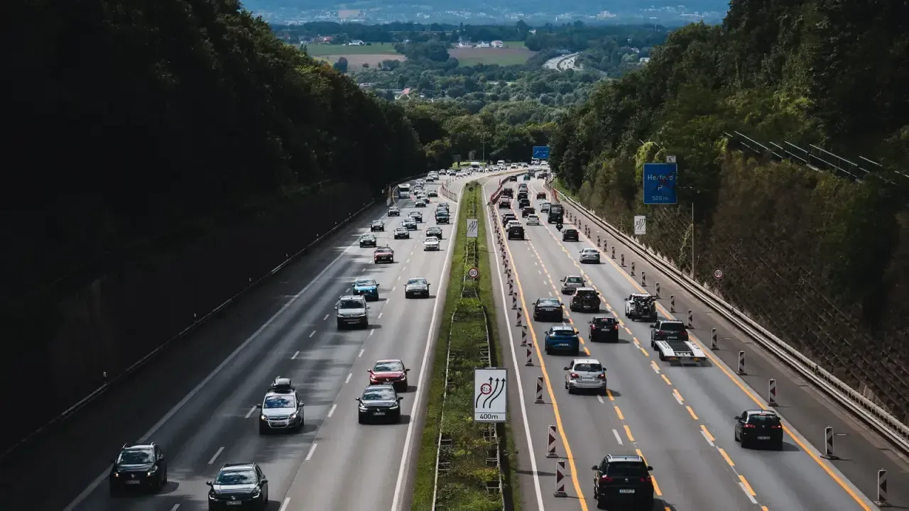 A multi-lane German motorway with dense traffic through wooded hills near Herford